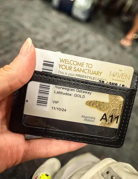 A close-up of a hand holding a Norwegian Getaway Haven VIP cruise card, displayed in a black wallet with gold lettering.