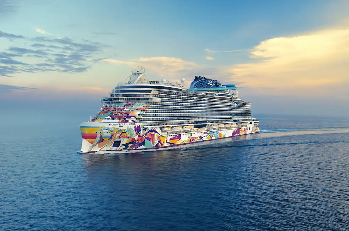 Norwegian Aqua, Norwegian Cruise Line’s first Prima Plus class ship, sailing at sea with its colorful hull artwork designed by Allison Hueman.